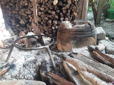 Endonezya kırsal mutfağında odun sobasında geleneksel bir çaydanlık. Dağınık odun ve küller otantik ve doğal kırsal yaşam atmosferini tamamlıyor..