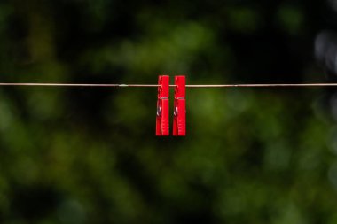 İnce bir ipe asılı kırmızı mandalların net bir görüntüsü..