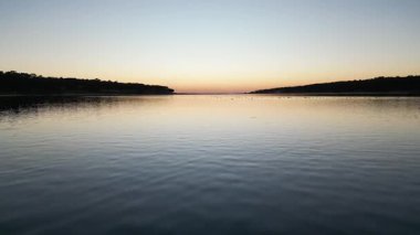 Gölün üzerinde gün batımı su yüzeyine yansıyor.