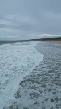 Sahilde dalgalı güzel bir sahilin dikey görüntüsü.