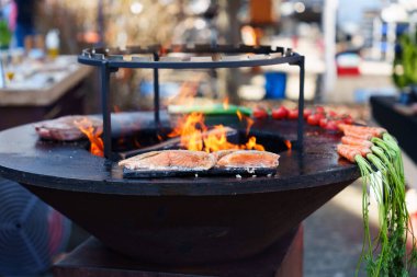 Izgara et ve taze sebzeler arka planda alevler olan bir ızgarada pişiyor. Barbekü partisi ve yemek konsepti için mükemmel..