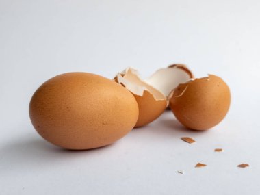 Beyaz arka planda birkaç kırık tavuk yumurtası ve bozulmamış tavuk yumurtaları var.