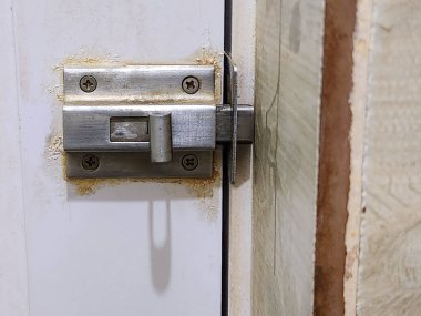 Kare şeklinde paslanmaz çelik bir banyo kapısı alüminyum bir kapıya monte edilmiş.