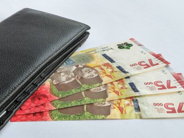 Cüzdan ve 75 bin rupiah banknotlar sınırlı sayıda üretilen beyaz arka planda izole edilmiş.