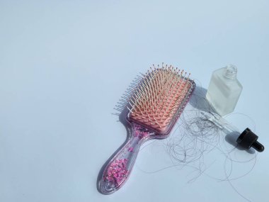 Saçları tarandıktan sonra dökülen pembe saç tarağı ve sağlıklı olmak için şişedeki saç vitaminleri. beyaz arkaplanda izole