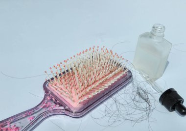Saçları tarandıktan sonra dökülen pembe saç tarağı ve sağlıklı olmak için şişedeki saç vitaminleri. beyaz arkaplanda izole