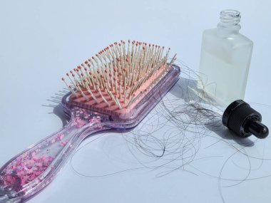 Saçları tarandıktan sonra dökülen pembe saç tarağı ve sağlıklı olmak için şişedeki saç vitaminleri. beyaz arkaplanda izole