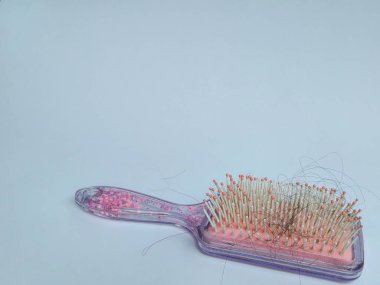 pink hair comb and hair that falls out after combing. isolated on white background