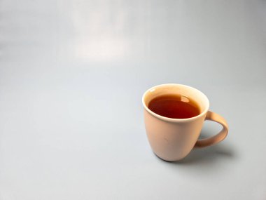 Açık mavi arka planda izole edilmiş bir bardak sıcak tatlı çay.