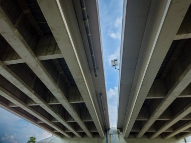 Kiriş kirişli sağlam beton bir yapısı olan üst geçitin perspektiften görünüşü. İnce bulutlu mavi gökyüzü köprünün boşlukları arasında belli belirsiz görünür..