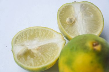 Bütün bir kireçin dış ve iç yüzey dokusu ve beyaz bir arka planda iki parçaya ayrılmış bir kireç.