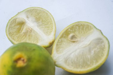 Bütün bir kireçin dış ve iç yüzey dokusu ve beyaz bir arka planda iki parçaya ayrılmış bir kireç.