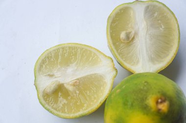 Bütün bir kireçin dış ve iç yüzey dokusu ve beyaz bir arka planda iki parçaya ayrılmış bir kireç.