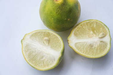 Bütün bir kireçin dış ve iç yüzey dokusu ve beyaz bir arka planda iki parçaya ayrılmış bir kireç.