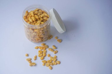 Beyaz arka planda izole edilmiş cam kavanozdaki tuzlu fıstık atıştırmalıkları.