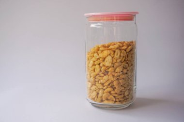 Beyaz arka planda izole edilmiş cam kavanozdaki tuzlu fıstık atıştırmalıkları.