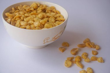 Beyaz arka planda izole edilmiş kasede tuzlu fıstık atıştırmalığı.