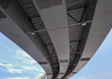 Otoyol kavşağındaki bir üstgeçitin alt görüntüsünde kavisli çelik yapıdan yapılmış üç kiriş var.