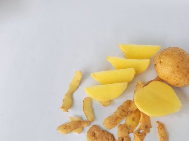 Kabuğu soyulmamış ve kesilmiş patatesler beyaz arka planda izole edilmiş.