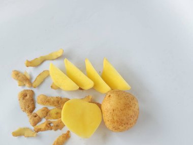 Kabuğu soyulmamış ve kesilmiş patatesler beyaz arka planda izole edilmiş.