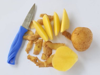 Soyulmamış ve kesilmiş patatesler, beyaz arka planda izole edilmiş kabuk ve bıçakla.