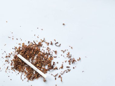 Bir yığın tütün ve beyaz arka planda izole edilmiş bir sigara.