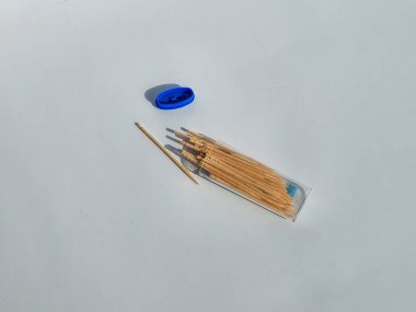 Sadece bir sivri uçlu bambu kürdanları ve beyaz arkaplanda izole edilmiş küçük şeffaf ambalajlar.