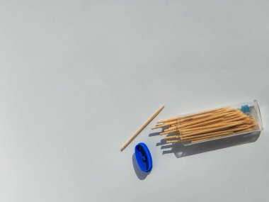 Sadece bir sivri uçlu bambu kürdanları ve beyaz arkaplanda izole edilmiş küçük şeffaf ambalajlar.