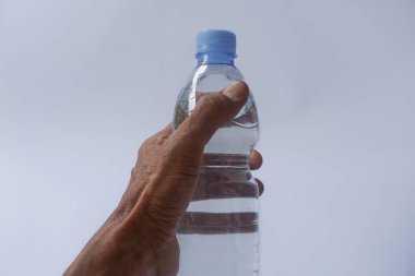 Beyaz arka planda plastik ambalajda bir şişe maden suyu tutan el.