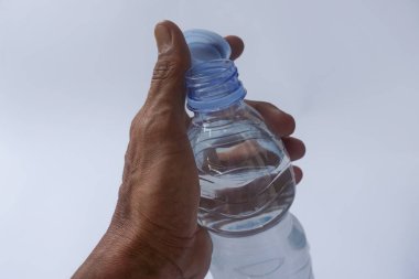 Beyaz arka planda plastik ambalajda bir şişe maden suyu tutan el.