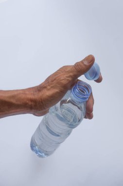 Beyaz arka planda plastik ambalajda bir şişe maden suyu tutan el.