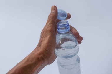 Beyaz arka planda plastik ambalajda bir şişe maden suyu tutan el.