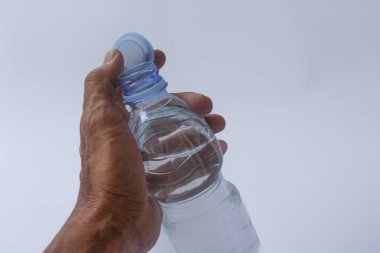 Beyaz arka planda plastik ambalajda bir şişe maden suyu tutan el.
