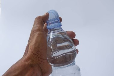Beyaz arka planda plastik ambalajda bir şişe maden suyu tutan el.
