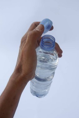 Beyaz arka planda plastik ambalajda bir şişe maden suyu tutan el.