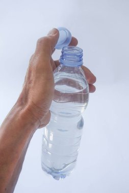 Beyaz arka planda plastik ambalajda bir şişe maden suyu tutan el.