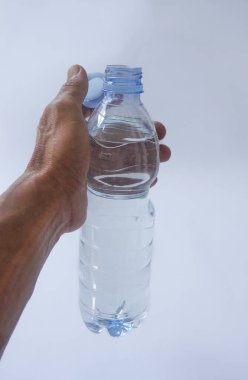 Beyaz arka planda plastik ambalajda bir şişe maden suyu tutan el.
