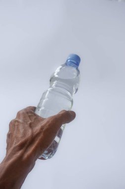Beyaz arka planda plastik ambalajda bir şişe maden suyu tutan el.