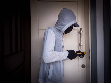 Bir hırsızın levye kullanarak evin kapısını açtığı görüntüsü.
