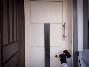 Bir hırsızın levye kullanarak evin kapısını açtığı görüntüsü.