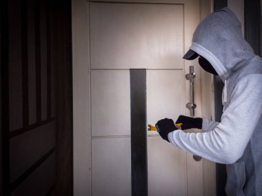 Bir hırsızın levye kullanarak evin kapısını açtığı görüntüsü.