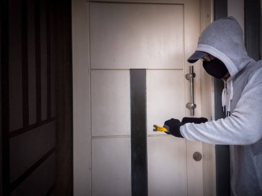 Bir hırsızın levye kullanarak evin kapısını açtığı görüntüsü.