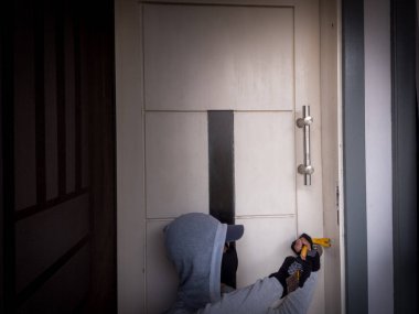 Bir hırsızın levye kullanarak evin kapısını açtığı görüntüsü.