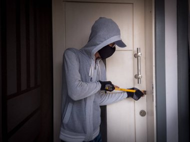 Bir hırsızın levye kullanarak evin kapısını açtığı görüntüsü.