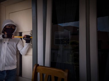 Bir hırsızın levye kullanarak evin kapısını açtığı görüntüsü.