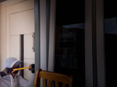 Bir hırsızın levye kullanarak evin kapısını açtığı görüntüsü.