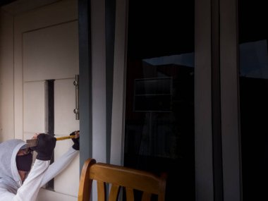 Bir hırsızın levye kullanarak evin kapısını açtığı görüntüsü.