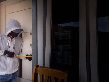 Bir hırsızın levye kullanarak evin kapısını açtığı görüntüsü.