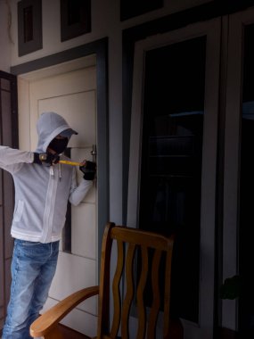 Bir hırsızın levye kullanarak evin kapısını açtığı görüntüsü.