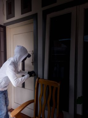 Bir hırsızın levye kullanarak evin kapısını açtığı görüntüsü.